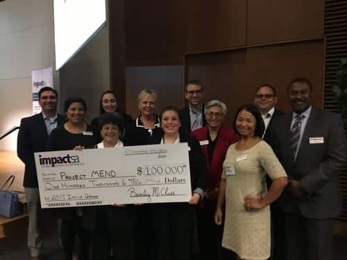 Bottom Row, L to R: Irma Lopez (volunteer), Stephanie Kotick (Program Specialist), Melinda Rodriguez (Board Member) Middle Row, L to R: Marcie Casas (Board Member), Denise Bennett (Director of Operations & Development), Cathy Valdez (CEO), Dexter Moon (Board Member) Back Row, L to R: Carey Quackenbush (Board Member), Allie Rodriguez (Programs Manager), Matt Swantner (Board Member), Joe Talamantez (Warehouse Manager) Project MEND poses with Impact San Antonio Grant Award check